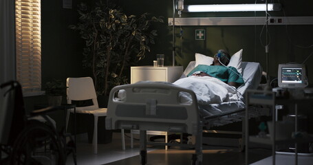 African woman in an oxygen mask is lying in a hospital room in a serious condition, in a coma,...