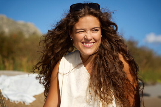 Mischievous young woman winking during sunny day