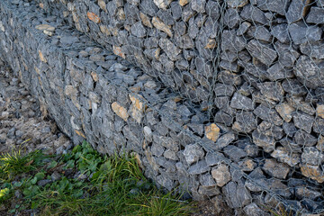 This image features a closeup view of a rustic stone wall, showcasing vibrant green grass protruding from the crevices and cracks, highlighting the beauty of natures resilience