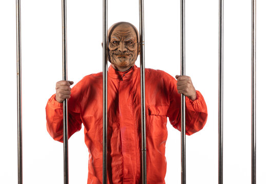 Portrait of a male prisoner behind bars on a white background