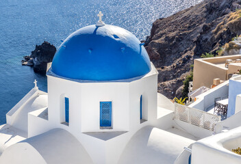 Wonderful white church with a blue dome and the coastline of  the island of Santorini, Greece