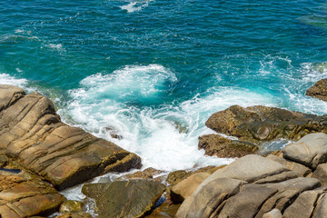 Waves crashed onto the shore with large rocks.