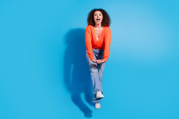 Photo of wavy haired model woman wearing orange cardigan and jeans boogie woogie move at discotheque isolated on blue color background