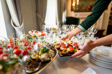 A close-up of a hand arranging gourmet appetizers on a table at an elegant event, showcasing a...