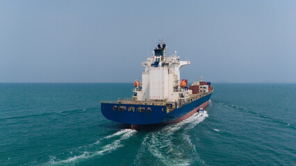 Aerial top view over international containers cargo ship at industrial import-export port prepare to load containers with big container loader ship vessel. global transportation and logistic business