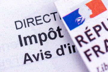 Gros plan du mot "impôt", avec le logo de la République Française, sur un avis d'imposition sur le revenu envoyé par la direction des finances publiques aux contribuables français