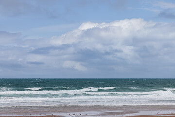 Fototapeta premium Vibrant blue sky with fluffy clouds over the deep green sea at Strandhill, Ireland, showcasing the vivid colors of the ocean and sky