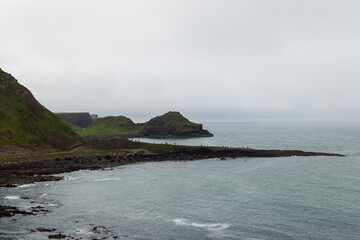 Tourists explore the iconic basalt columns at Giant Causeway, Northern Ireland, stretching out into...