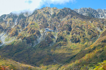 Obraz premium Kurobedaira Station, Tateyama, Toyama, Chubu, Japan, Lush green mountains display vibrant foliage, with rocky peaks under a bright blue sky