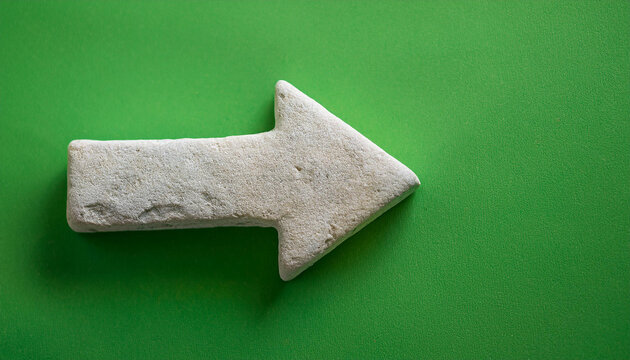 White stone arrow pointing right on green backdrop. Direction guide.