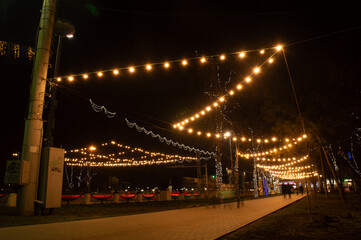 A city street at night with many lights hanging from the street lights.