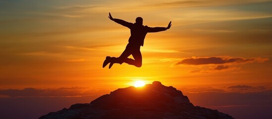 Silhouette of a Person Jumping Joyfully Against a Vibrant Sunset Sky on a Mountain Peak