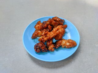 Golden, crispy chicken karaage sits perfectly on a vibrant blue plate, each piece glistening with a savory barbeque sauce glaze.