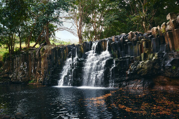 Obraz premium Beautiful Rochester Falls in Mauritius, Africa, showcasing cascading waters over rugged volcanic rock formations, surrounded by lush tropical greenery