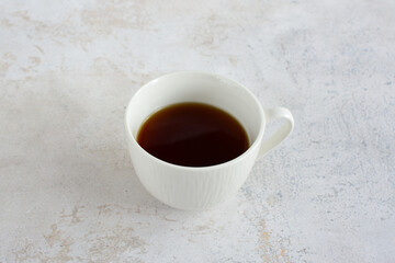 a white cup with strong coffee in it sits on a marble surface