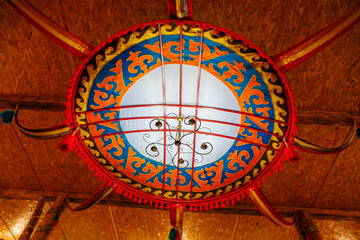 A large, colorful, ornate chandelier hangs from the ceiling, kyrgyz authentic nomadic culture in...