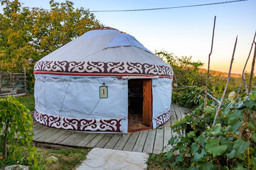 A round tent sits in a field, kyrgyz authentic nomadic yurt