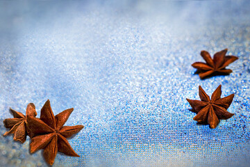 Beautiful winter background. Star anise on blue fabric covered with frost