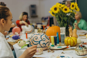 Children and adults painting pumpkins for Halloween, enjoying a fun and creative activity together.