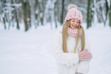 Beautiful blonde girl in winter warm clothes, on vacation in the park.