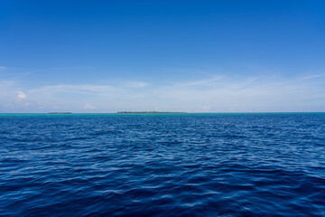 Obraz premium Mataking Island and Small Mataking Island (Pulau Mataking Kecil) on the horizon, from a far distance with multiple groups of tourists snorkelling and scuba diving.