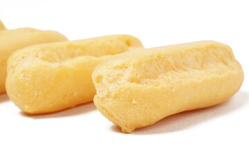 Neatly stacked mini cream puffs (sus kering) in a thumb-sized, golden-yellow shape. Photographed on a white background. Perfect as a light snack.