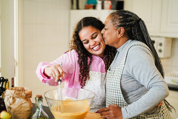 African mother and daughter having fun preparing free sugar cake at home - Family lifestyle and...