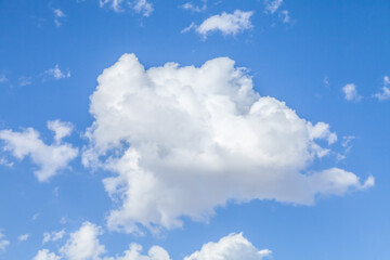 Big white puffy cumulus cloud over clear deep blue sky closeup background image