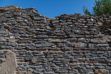 Old heritage wall made of stones of different shapes and sizes, built without cement. Stone wall texture. Background