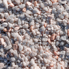 Decorative filler for flower beds of quartz pebbles in white color. Close-up view from the top.