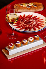 Elegant tapas arrangement, a glass of white wine and a rustic wooden board.