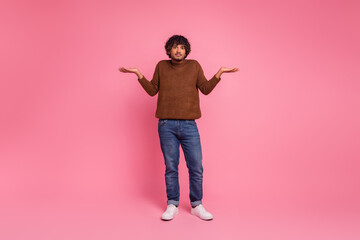 Photo of funny uncertain unsure man wear trendy brown clothes raise hands isolated on pink color background