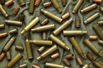Many used rifle cartridges on military camo green fabric background