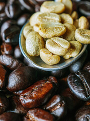 Top view green coffee bean on a stainless steel spoon on roasted coffee bean  background, Close-up, Close-up of unroasted coffee bean