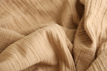 Texture of crumpled linen fabric under natural light in peach fuzz color