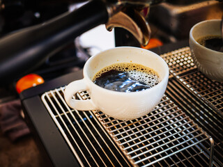 Close-up of Americano pouring from the coffee machine into a cup. Professional coffee brewing black coffee