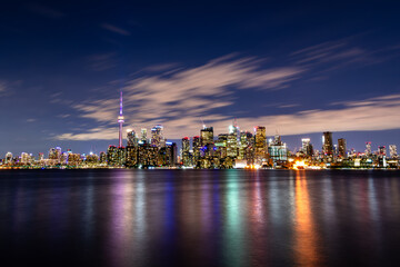 Fototapeta premium City skyline is reflected in water at night, creating a stunning view