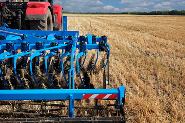 Rear view of a large tractor  with a knife plow in a field. Start tillage after harvest.