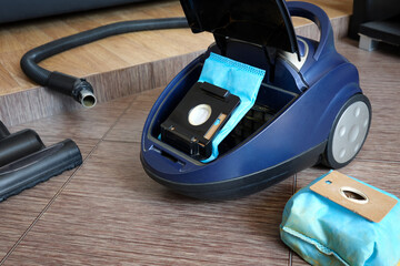 Close-up of open home vacuum cleaner and new clean cleaning bag.