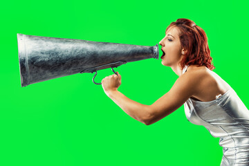 Young woman shouting through megaphone on green screen backgroun