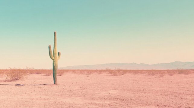 A single saguaro cactus stands tall in the desert, with mountains in the distance. The sky is a pale blue, and the sand is a soft pink. - Powered by Adobe