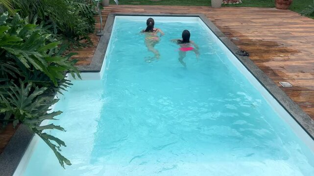 m&atilde;e e filha juntas e felizes na piscina 