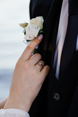 Elegant Wedding Close-Up of a Bride's Hand Adjusting a Groom's Boutonniere