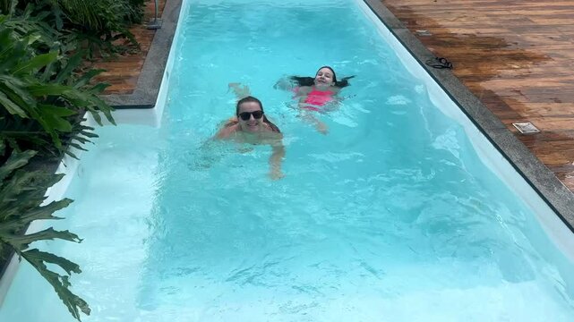 m&atilde;e e filha juntas e felizes na piscina 