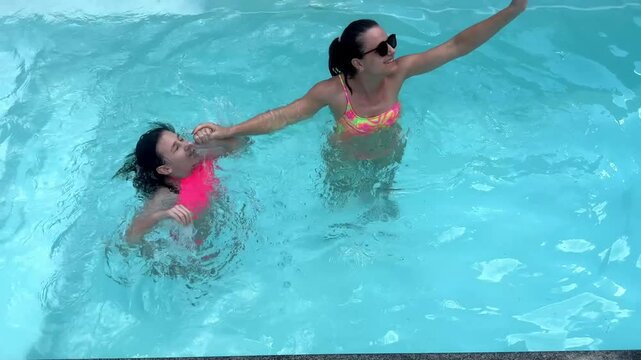 m&atilde;e e filha juntas e felizes na piscina 