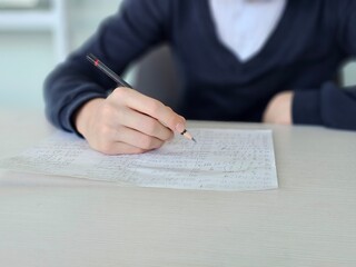 A student writes notes in class, focusing on a piece of paper