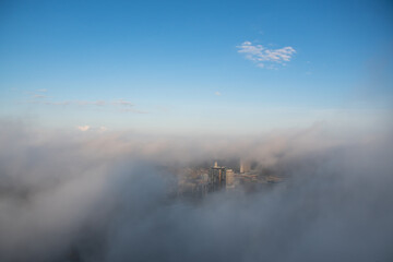 A breathtaking aerial view of a cityscape surrounded by thick fog and clouds