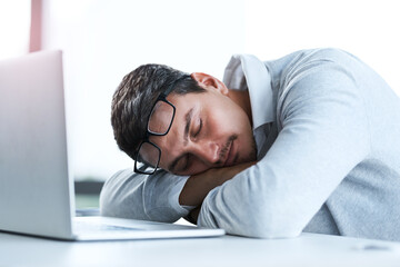 Tired businessman, sleeping and rest with laptop on desk for lazy day, done or finished at office. Young, man or employee asleep on table with computer for fatigue, burnout or dreaming at workplace