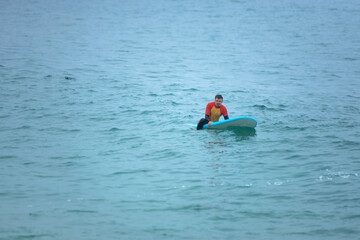Handsome surfer man in the ocean. Surfing classes. Amateur surfer. Photo for surfing school advertising on social media.