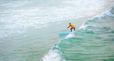 Surfer. Teenage girl learning to surf on foam in the ocean. First surfing lesson. Amateur surfer....